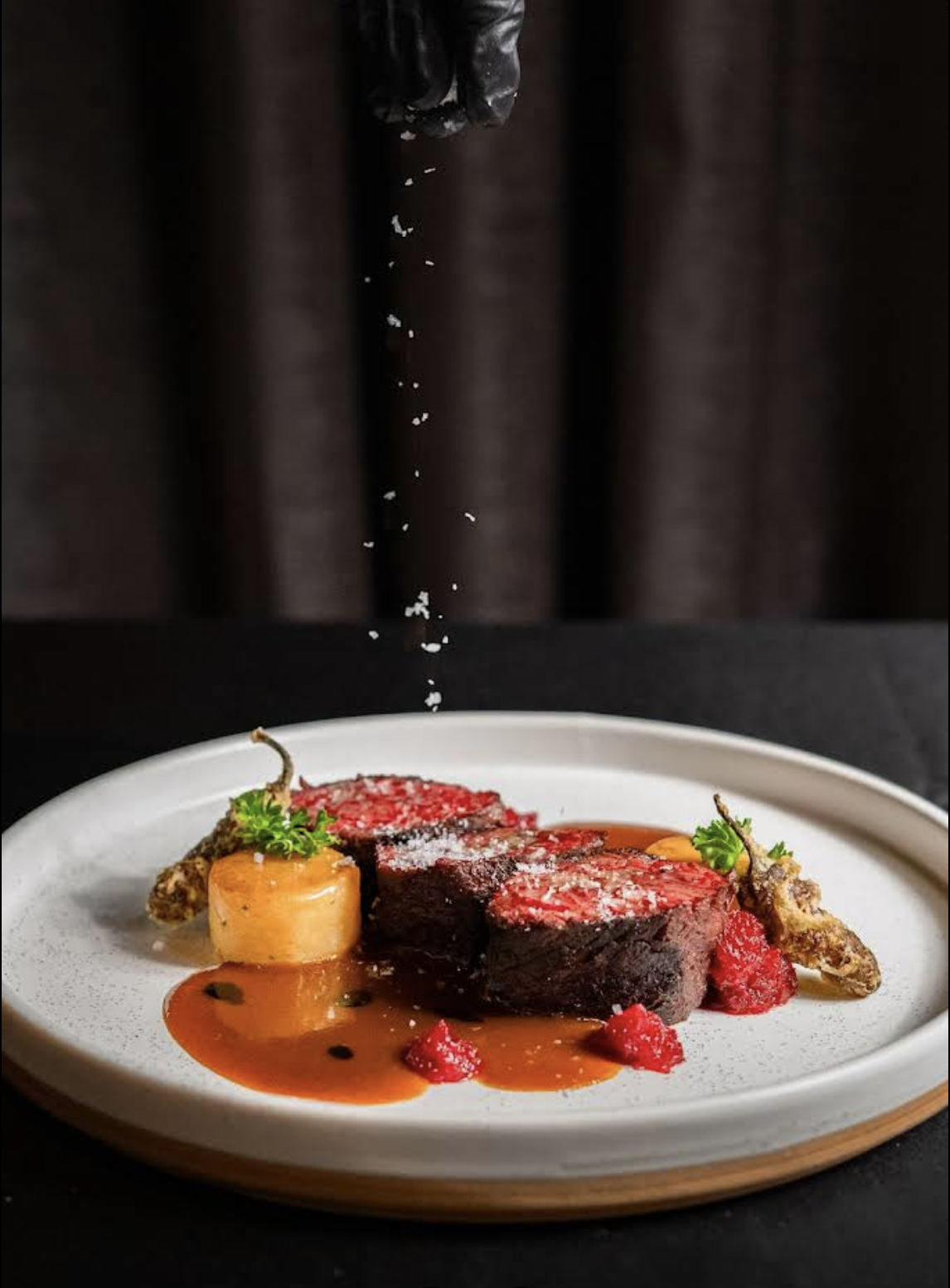 Plated PRIME steak with warm sauce and finishing salt